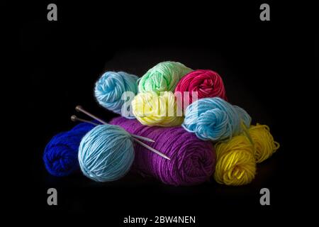 Buntes Garn mit Lochnadel auf schwarzem Hintergrund Stockfoto