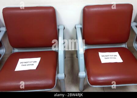 Stühle im Krankenhaus mit Blättern Papier, nicht auf diesem Stuhl sitzen. Soziale Distanzierung. Stockfoto