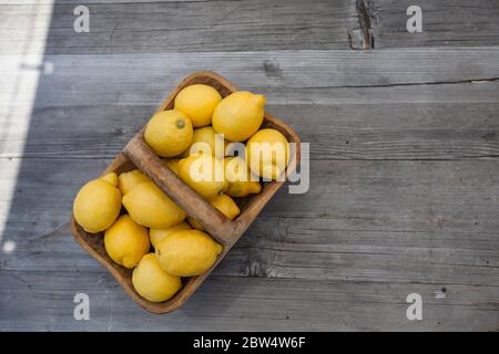 Zitronen in einem Korb auf einem Holztisch Stockfoto