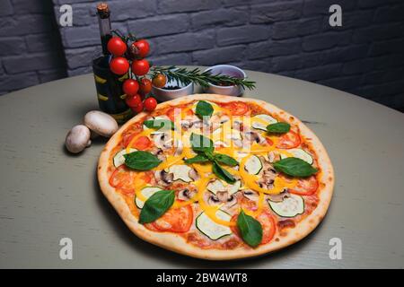 Leckere vegetarische Pizza mit Pilzen, Zucchini, Tomaten, Pfeffer und Basilikum Stockfoto
