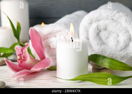 Komposition mit Kerzen, Handtüchern, Steinen und Orchidee auf Holztisch. Zen-Konzept Stockfoto