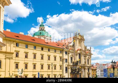 Die Kirche des Heiligen Nikolaus ist Barock-katholische Kirche in der Kleinseite, Säule der Heiligen Dreifaltigkeit auf Platz in Mala Strana Bezirk, blauer Himmel weiße Wolken Hintergrund, Böhmen, Tschechische Republik Stockfoto