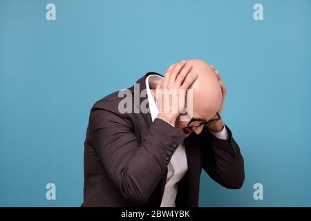 Paranoider reifer Mann, der seine Ohren bedeckt und von lauten Geräuschen genervt wird. Stockfoto