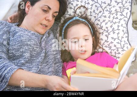 Mutter und Tochter liegen auf dem Bett und lesen ein Märchbuch. Top-Down-Shooting. Home Schulkonzept mit leerem Kopieraum für Text des Herausgebers. Stockfoto