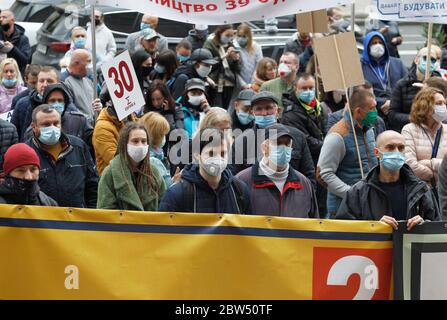 Investoren von Wohnkomplexen tragen Gesichtsmasken vor dem Kiewer Rathaus versammeln, wie sie an der Demonstration teilnehmen.etwa tausend Investoren der Bau Wohnanlagen, die in Wohnungen von Arkada Bank investiert blockiert die zentrale Straße Chreschatyk in Kiew und verbrannt Flares während ihres Protests gegen die Suspendierte Bau ihrer investierten Häuser, wie lokale Medien berichteten. Die Demonstranten fordern den Wiederaufbauvorgang der Wohnanlagen. Stockfoto