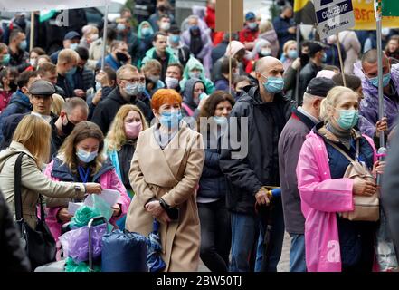 Investoren von Wohnkomplexen tragen Gesichtsmasken vor dem Kiewer Rathaus versammeln, wie sie an der Demonstration teilnehmen.etwa tausend Investoren der Bau Wohnanlagen, die in Wohnungen von Arkada Bank investiert blockiert die zentrale Straße Chreschatyk in Kiew und verbrannt Flares während ihres Protests gegen die Suspendierte Bau ihrer investierten Häuser, wie lokale Medien berichteten. Die Demonstranten fordern den Wiederaufbauvorgang der Wohnanlagen. Stockfoto