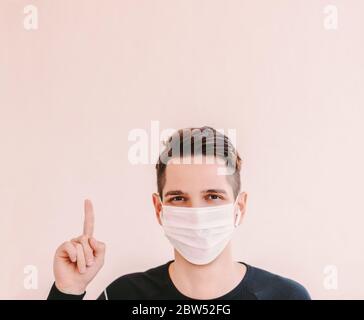 Portrait glücklich Mann Fitness-Trainer in Schutzmaske zeigt mit Zeigefinger auf Hintergrund kopieren Raum. Junge Sportmann in medizinischen Gesichtsmaske zeigen Stockfoto