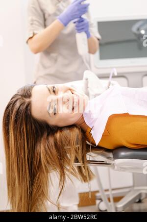 Junge Patientin wartet auf dem Tisch und schaut auf die Kamera und lächelt Stockfoto