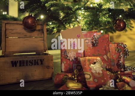 Weihnachtsgeschenke neben einer Holzkiste unter der Tanne Stockfoto