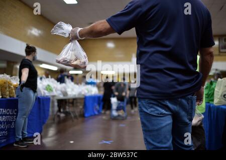 New York City, USA. Mai 2020. Während der COVID-19 tragen Freiwillige Schutzmasken und Handschuhe und helfen, gespendete Lebensmittel für Menschen zu bereiten, die Hilfe in der St. Finbar Catholic Church in New York, New York, 29. Mai 2020, suchen. Mit genügend Nahrungsmittelpaketen für 1500 Personen verteilten die katholischen Wohltätigkeitsorganisationen Brooklyn und Queens Lebensmittel an diejenigen, die an Unsicherheiten durch die Auswirkungen der Coronavirus-Pandemie und deren Auswirkungen auf die Wirtschaft leiden. (Anthony Behar/Sipa USA) Credit: SIPA USA/Alamy Live News Stockfoto