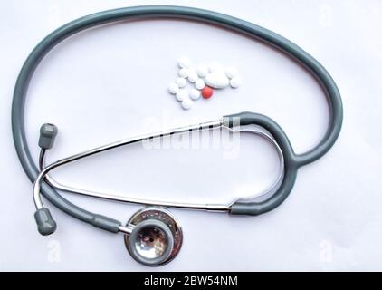 Pillen verschüttet aus einer Pillenflasche mit einem Stethoskop im Rahmen und isoliert auf weißem Hintergrund. Draufsicht mit Kopierbereich. Medizinkonzept Stockfoto