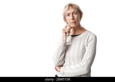 Freistil. Ältere Frau in Pullover stehend isoliert auf weiß aussehende Kamera nachdenklich Stockfoto