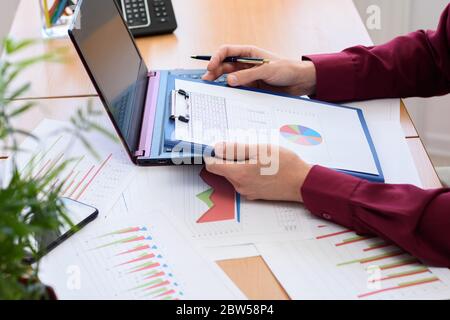 Nahaufnahme des Büroangestellten, der ein Tablet mit Dokumenten und Grafiken hält Stockfoto