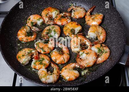 Königgarnelen mit Dill und Knoblauch werden in einer Pfanne gekocht Stockfoto