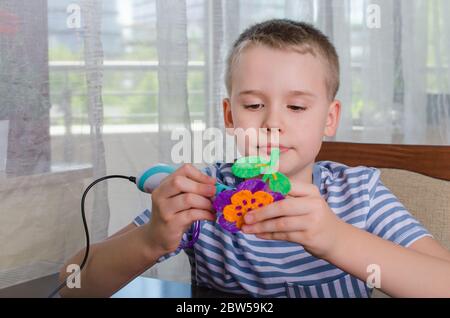 Junge mit 3D-Stift. Happy Kind macht Blume aus farbigen ABS-Kunststoff. Kreatives Hobby zu Hause, Technik, Freizeit, Bildungskonzept. Stockfoto