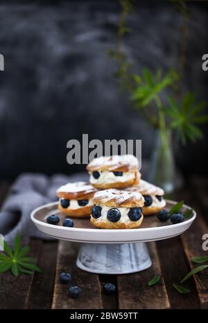 Cremefarbene Blätterringe (Choux-Gebäck) mit frischen Blaubeeren verziert Stockfoto