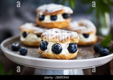 Cremefarbene Blätterringe (Choux-Gebäck) mit frischen Blaubeeren verziert Stockfoto