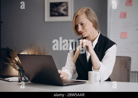 Smart Business Frau sitzt am Tisch und arbeitet auf Laptop Stockfoto