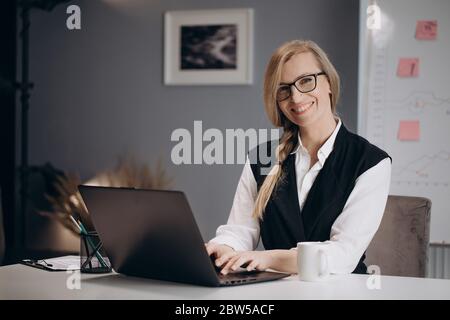 Lächelnde Frau in Brille, die im Büro am Computer arbeitet Stockfoto