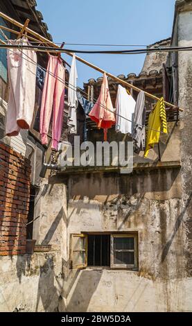 Tongli, Jiangsu, China - 3. Mai 2010: Nahaufnahme von bunten Wäsche, die von Bambusstange im Hof des heruntergekommenen Hutong-Hauses unter blauem Himmel hängt. Stockfoto