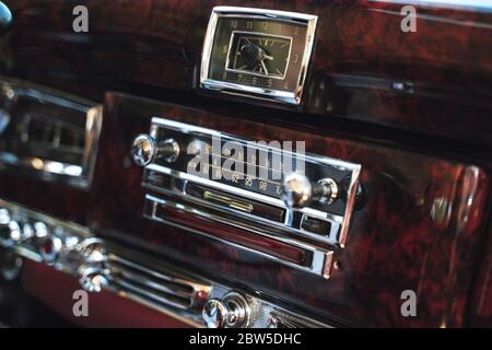 Luxus-Interieur des alten amerikanischen Oldtimer. Hölzerne dekorierte Instrumententafel mit Radio und Uhren. Stockfoto