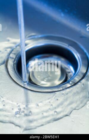 Fließendes Wasser, das das Loch des Spülbeckens herunterläuft. Stockfoto