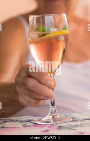 Nahaufnahme einer älteren Frau mit einem Glas Sommercocktail. Stockfoto