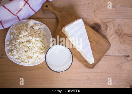 Leckere frische Milch auf einem weißen Holzhintergrund. Glas Milch, Käse auf dem Brett und Hüttenkäse. Blick von oben. Kopierraum Stockfoto