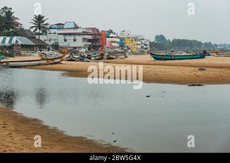 Fischerboote verstreuten sich an einem bewölkten Tag über Mahabalipuram Beach, Indien Stockfoto