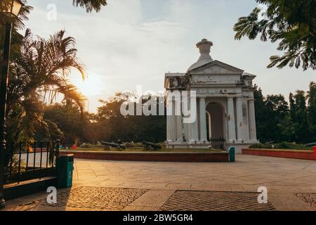 Die Sonne geht hinter einem griechisch-römischen Bogen im Zentrum des Bharathi Parks, Pondicherry, Indien, unter Stockfoto