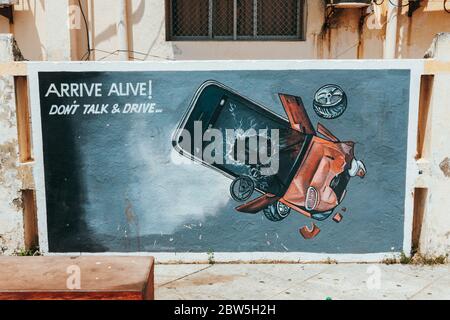 „Ankommen! Don't Talk & Drive' - eine handbemalte Werbung für sicheres Fahren in Pondicherry, Indien, die ein in ein Fahrzeug zerschmettertes Mobiltelefon darstellt Stockfoto