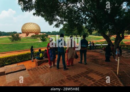 Indische Touristen vor Matrimandir, einer goldenen Kugelstruktur, die für die Meditation in der experimentellen Township Auroville, Indien, gebaut wurde Stockfoto