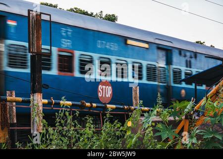 Ein Personenzug fährt an einem Stoppschild an einem Bahnübergang in Alappuzha, Kerala, Indien vorbei Stockfoto