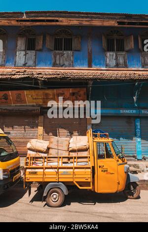 Eine mit Taschen und Kisten beladene Fracht-Auto-Rikscha vor einem Kolonialgebäude in Mattancherry, Kochi, Indien Stockfoto
