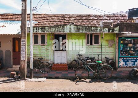 Fahrräder vor einem kleinen Haus in einer Straße in Kochi, Indien geparkt Stockfoto
