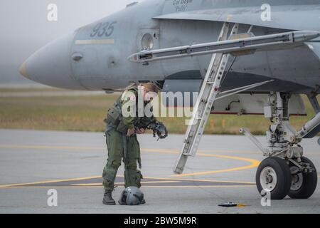 Saint John, New Brunswick, Kanada - 17. September 2017: Eine weibliche Jagdpilotin bereitet ihren Fluganzug vor, der neben einem CF-18 Hornet Kampfjet steht. Stockfoto