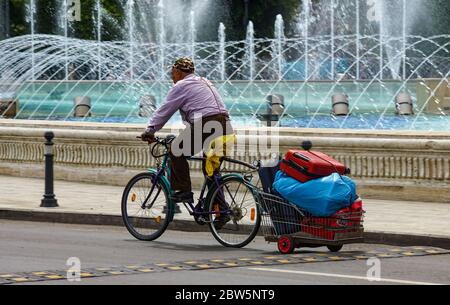 Bukarest, Rumänien - 24. Mai 2020 Alter Mann auf einem Fahrrad mit einem Wagen mit mehreren alten Koffern, in der Innenstadt von Bukarest. Rumänische Regierung hob r Stockfoto