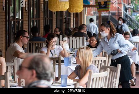 Washington, Unbunden Staaten. Mai 2020. Eine Kellnerin serviert am 29. Mai 2020 in einem Restaurant im Adams Morgan-Viertel von Washington, DC. Die DC Metro Region beginnt wieder zu öffnen, beginnend mit Outdoor-Restaurants nach der fast drei Monate Sperre aufgrund der COVID-19 Pandemie. Foto von Kevin Dietsch/UPI Quelle: UPI/Alamy Live News Stockfoto