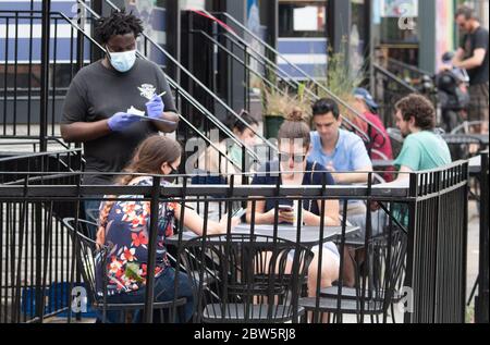 Washington, Usa. Mai 2020. Ein Kellner nimmt am 29. Mai 2020 in einem Restaurant im Adams Morgan-Viertel von Washington, DC, eine Bestellung auf. Die DC Metro Region beginnt wieder zu öffnen, beginnend mit Outdoor-Restaurants nach der fast drei Monate Sperre aufgrund der COVID-19 Pandemie. Foto von Kevin Dietsch/UPI Quelle: UPI/Alamy Live News Stockfoto