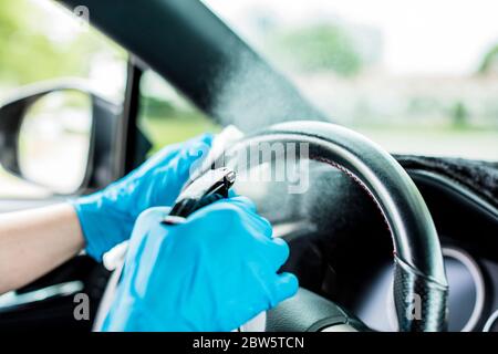 Hände mit blauen Handschuhen, dann Desinfektionsmittel und Reinigung des Autos Stockfoto