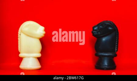 Schachfiguren Ritter einander gegenüberstellen für einen Standoff mit verschwommenen isoliert auf rotem Hintergrund. Konfrontation von Schachfiguren.Schachfiguren Ritter auf C Stockfoto