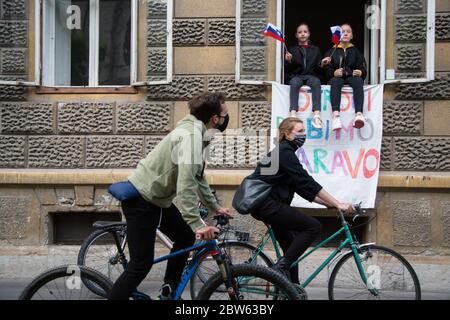 Ljubljana, Slowenien. Mai 2020. Zwei Mädchen sitzen auf einem Fenster und schwenken während der Demonstration slowenische Fahnen.Jeden Freitag protestieren Tausende Menschen in Ljubljana gegen die Regierung von Premierminister Janez Janša, weil sie die Korruption und undemokratische Herrschaft seiner Regierung beschuldigt haben. Quelle: SOPA Images Limited/Alamy Live News Stockfoto