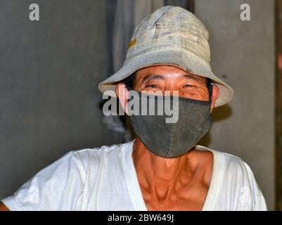 Vietnamesische Reismühlenarbeiter trägt eine waschbare improvisierte Anti-Verschmutzung Tuch Gesichtsmaske. Stockfoto