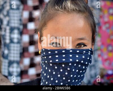 Junge indische Angami Frau mit schönen Augen bedeckt den unteren Teil ihres Gesichts mit einem blauen Tupfen-Schleier. Stockfoto