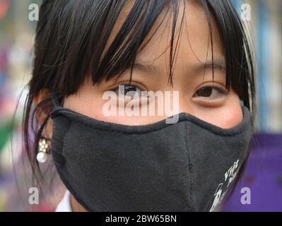 Asiatische Mädchen mit schönen Augen bedeckt ihre Nase und Mund mit einer wiederverwendbaren, waschbaren schwarzen Baumwolle Gesichtsmaske. Stockfoto