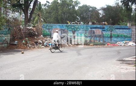 Alter Mann, der mit dem Fahrrad nach Hause fährt. Mann, der Gesichtsmaske trägt und Fahrrad fährt in der leeren Straße. corona sperren. Stockfoto