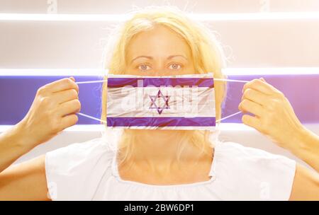 Frau mit einer Israel-Flagge auf einer chirurgischen Maske. Konzept des Ausbruchs und der Quarantäne für die Coronavirus-Pandemie in Israel. Antivirale und Impfstoffforschung Stockfoto