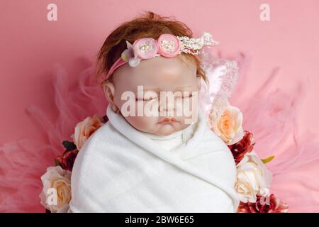 Schöne Baby wiedergeboren Puppe in Blumen, professionelle neugeborene Fotoshooting. Stockfoto