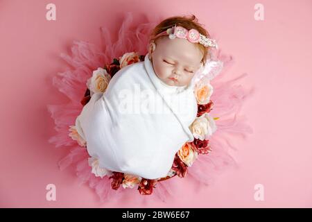 Schöne Baby wiedergeboren Puppe in Blumen, professionelle neugeborene Fotoshooting. Stockfoto