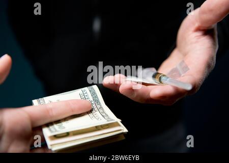 Nahaufnahme der Hände, die Geld gegen eine Dosis Drogen tauschen. Händler- und Käufertreffen Stockfoto